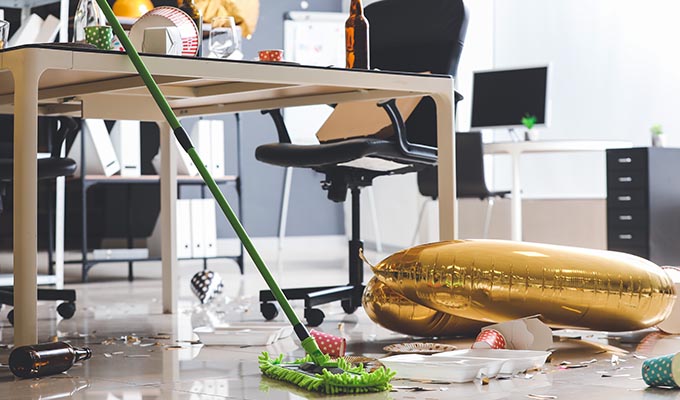 cleaning company in Nottingham, person sweeping under a desk after an office party.